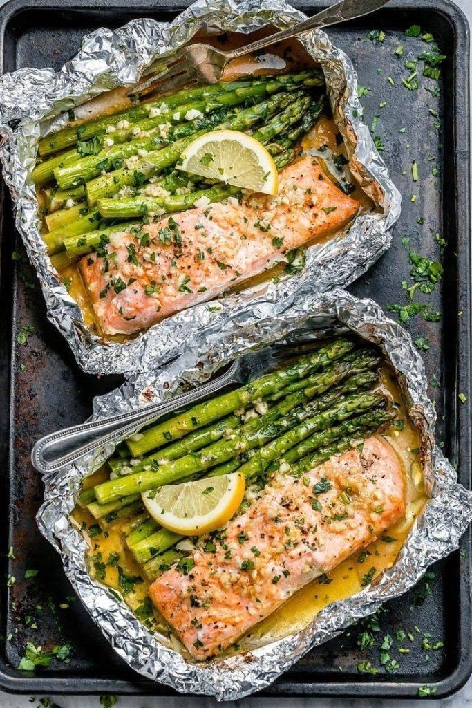 Salmone al forno in cartoccio con asparagi e salsa al burro all’aglio e limone .